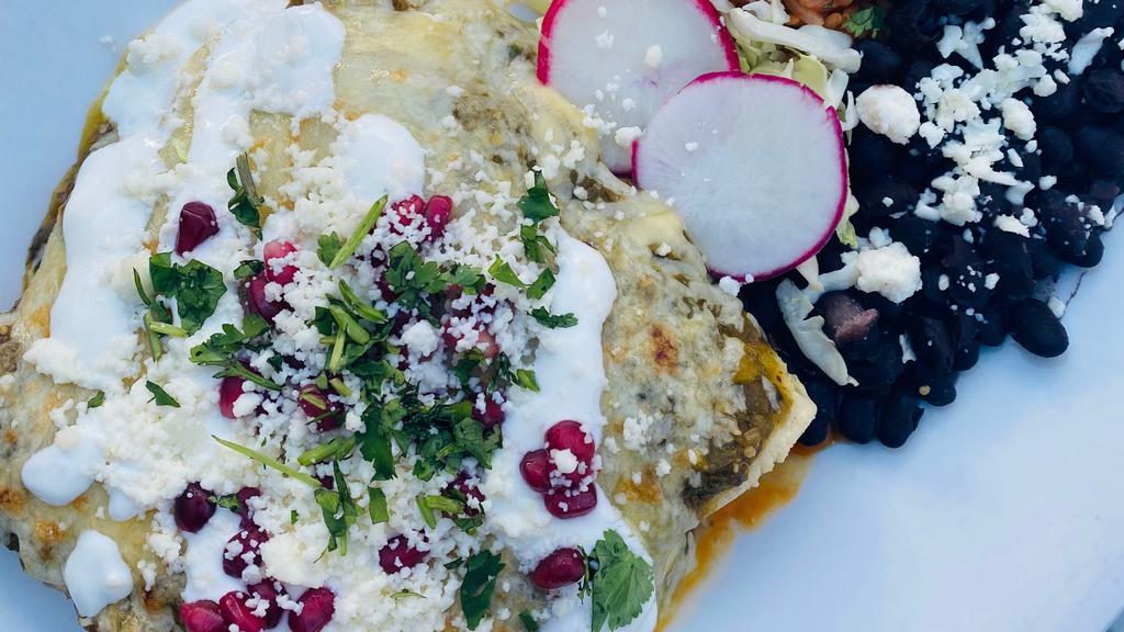 Enchiladas Suiza · corn tortilla, chicken tinga, salsa verde, manchego and jack cheeses, lime crema, pomegranate seeds, queso fresco, cilantro. served with spanish rice and braised black beans, cotija & cilantro
