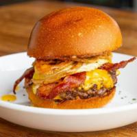 Brunch Burger · Beef patty, cheddar, house-made tot bun, bacon, sunny side up egg, avocado spread, crispy on...