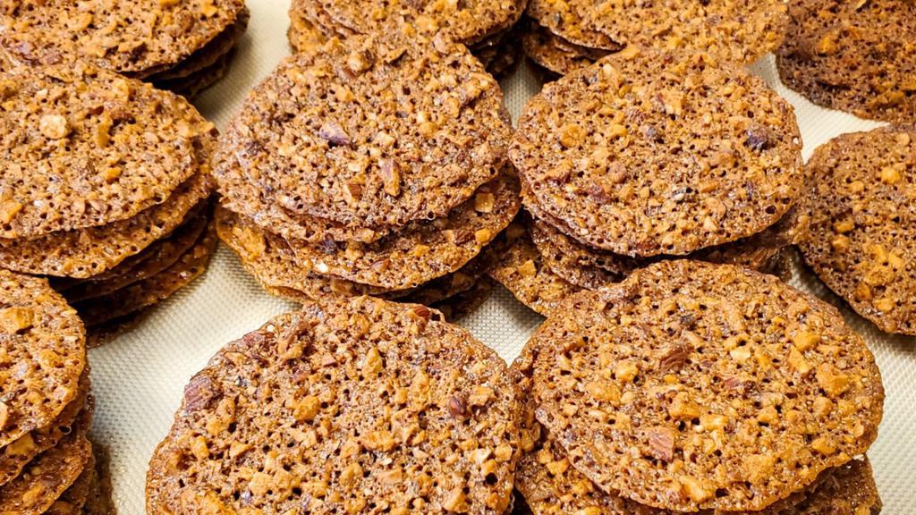Gluten Free Toffee Crisp · Our signature gluten free cookies. Thin layers of toffee mixed with almonds and pecans and dark chocolate in between. L