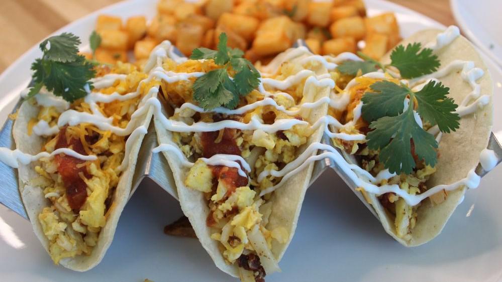 Juan'S Breakfast Tacos · Three corn tortillas filled with scrambled eggs, hash browns, jack cheese, topped with sour cream. Green chile chipotle hollandaise sauce & Pico de Gallo on side. Served with choice of hash browns or breakfast potatoes.