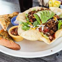 Taco Salad · Freshly fried tortilla shell filled with warm re-fried beans, taco meat, fresh salad greens,...