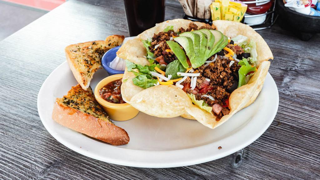 Taco Salad · Freshly fried tortilla shell filled with warm re-fried beans, taco meat, fresh salad greens, shredded cheddar & jack cheeses, sliced olives & diced fresh tomato & topped with avocado. Served with sour cream & our home-made salsa.
