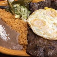Bistek Con Huevos · Hand cut steak with two over well eggs with beans and freshly hand made tortillas.