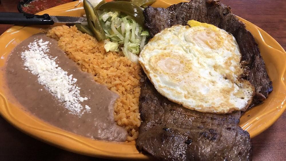 Bistek Con Huevos · Hand cut steak with two over well eggs with beans and freshly hand made tortillas.