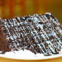 Torre Chocolate Cake · A decadent tower of rich chocolate cake, covered in chocolate shavings, drizzled with a vani...