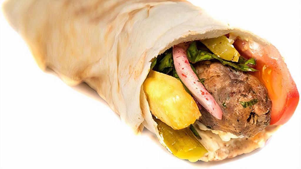 Lamb Kebab (Kafta) · Char-grilled lamb kebab kafta with hummus, onion, parsley, sumac, pickles, fries, and tomatoes.