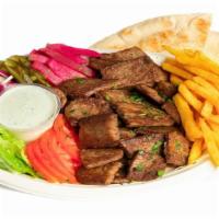 Lamb Gyro · Lamb gyro served with vegetables, pickles, pita bread, tzatziki sauce, rice, or fries.