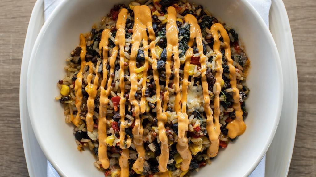 Fiesta Grain Bowl · Sauteed spinach, black beans, roasted corn, caramelized onion, roasted red peppers, grilled jalapeno, feta, chile crema, with a blend of 100% whole grain brown rice, black barley and daikon radish seeds.