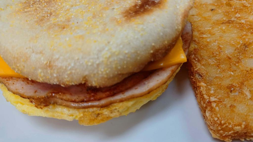Turkey And Egg English Muffin · Toasted English muffin with sliced ham, scrambled eggs and your choice of cheese, served with a patty of hash browns
