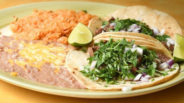 Tacos De Asada · Two pieces of street tacos with carne asada garnished with onions, cilantro and lime. Served with rice and beans.