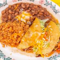 Garlic Pork Roast Soft Tacos · Two tacos topped with cheese, lettuce, and tomatoes with rice and beans.