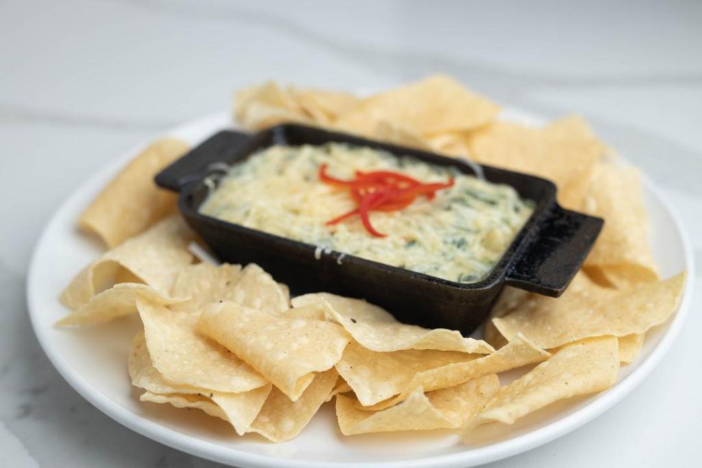 Artichoke Spinach Dip · Parmesan cream sauce prepared with spinach, artichokes, jalapeño, roasted red pepper, cayenne pepper and fresh garlic. Topped with melted White Cheddar and Parmesan cheese. Served with white corn tortilla chips.
