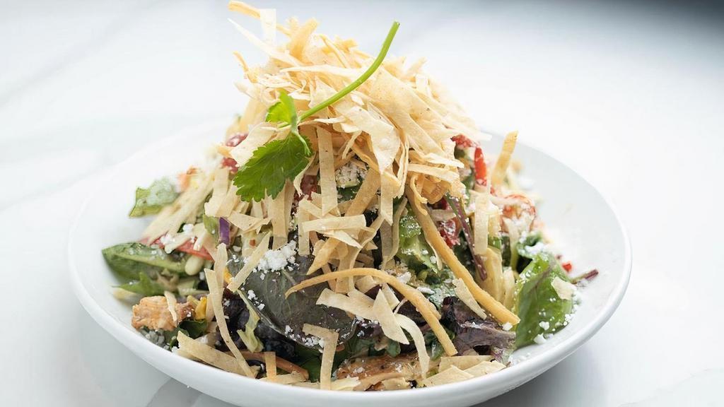 Southwest Smoked Chicken Salad · Mesquite smoked chicken, roasted sweet corn, red peppers, avocado, cherry tomatoes, marinated jicama and cilantro tossed with fresh spring greens, and our Napa slaw. Topped with Cotija cheese and crispy tortilla strips. Served with Cilantro Lime Vinaigrette.