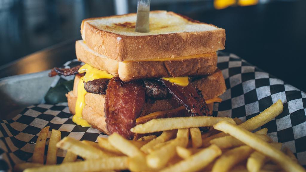 Twin Cam Burger · Burger topped with peppered bacon and nacho cheese dialed in between two grilled cheese sandwiches for buns.