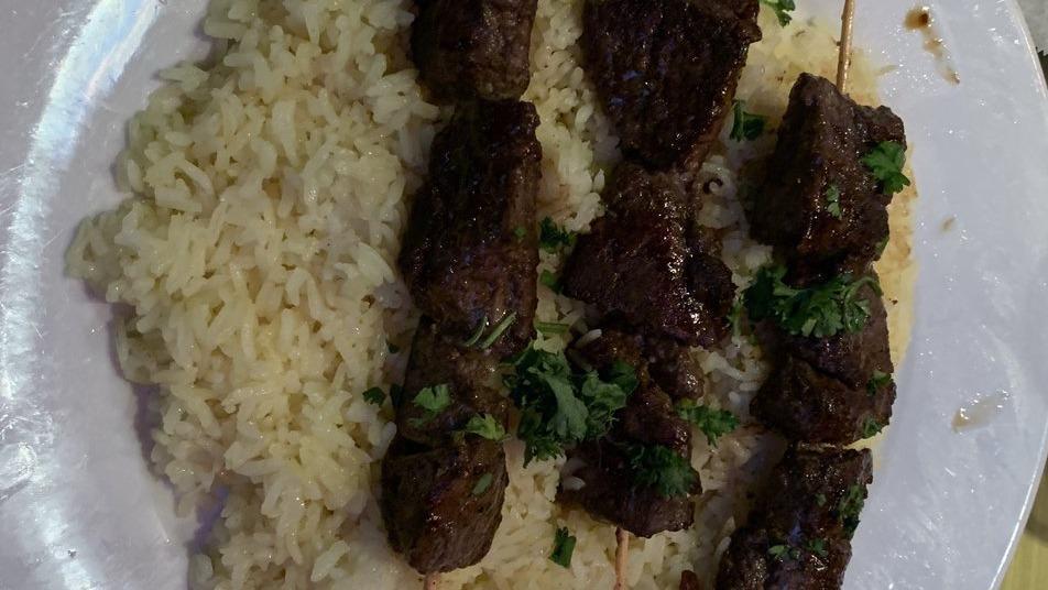Lamb Kebab · Tender marinated lamb. Two skewers served on a bed of our special flavored rice, with homemade garlic sauce and side salad.