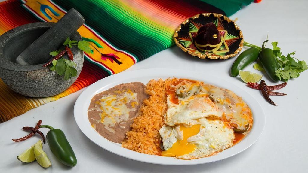 Huevos Rancheros Plate · Two fried eggs served upon lightly fried corn tortillas topped with tomato chili sauce and cheese served with a side of refried beans, spanish rice, and choice of corn or flour tortillas