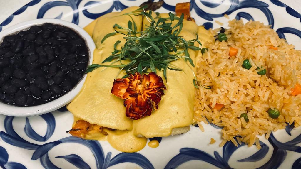 Enchiladas De Otoño · 100% Vegan Dish  Two corn tortillas filled with roasted sweet potato, bell pepper, eggplant, and golden beets. Topped with a yummy vegan cream sauce made with habaneros, cashews and spices. Served with vegan mexican rice and black beans.