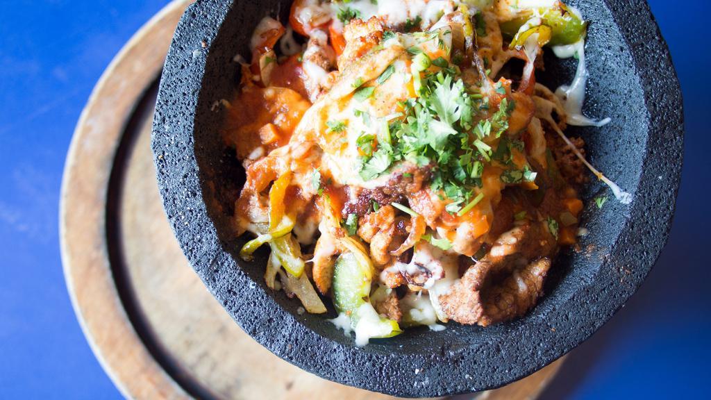 Molcajete · Steak and chicken fajita strips, bell peppers, onions and chorizo all covered with Jack cheese and roasted molcajete sauce. Served with pico de gallo, sour cream and guacamole.