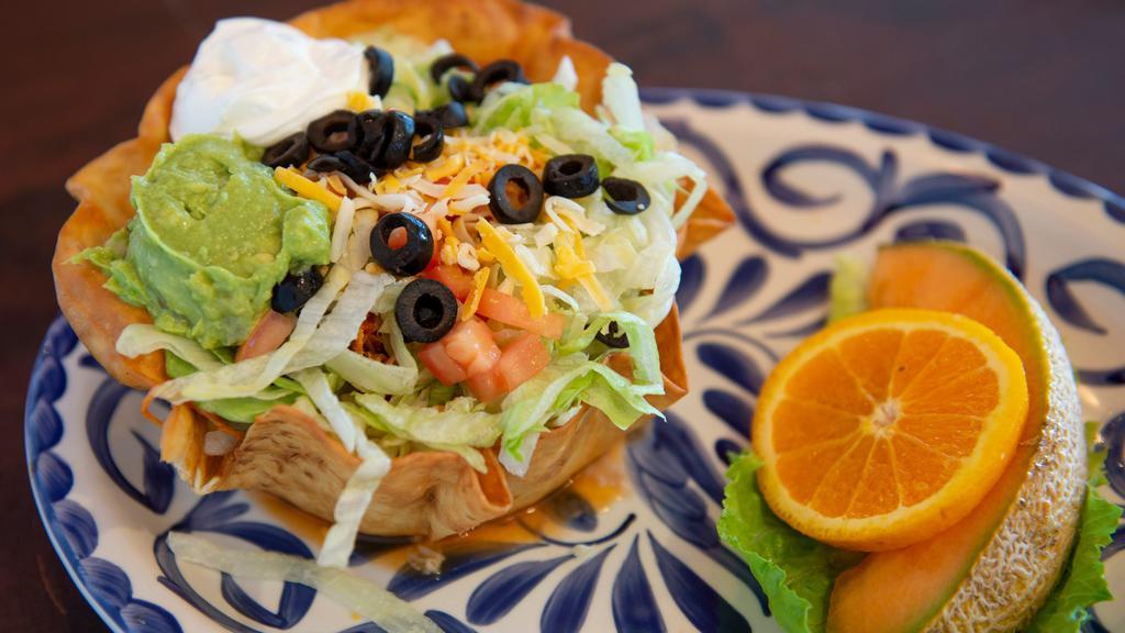 Taco Salad · A crispy flour tortilla bowl with choice of chicken, beef or picadillo. Topped with lettuce, tomatoes, cheese, olives, sour cream, and guacamole. Served with fresh fruit.