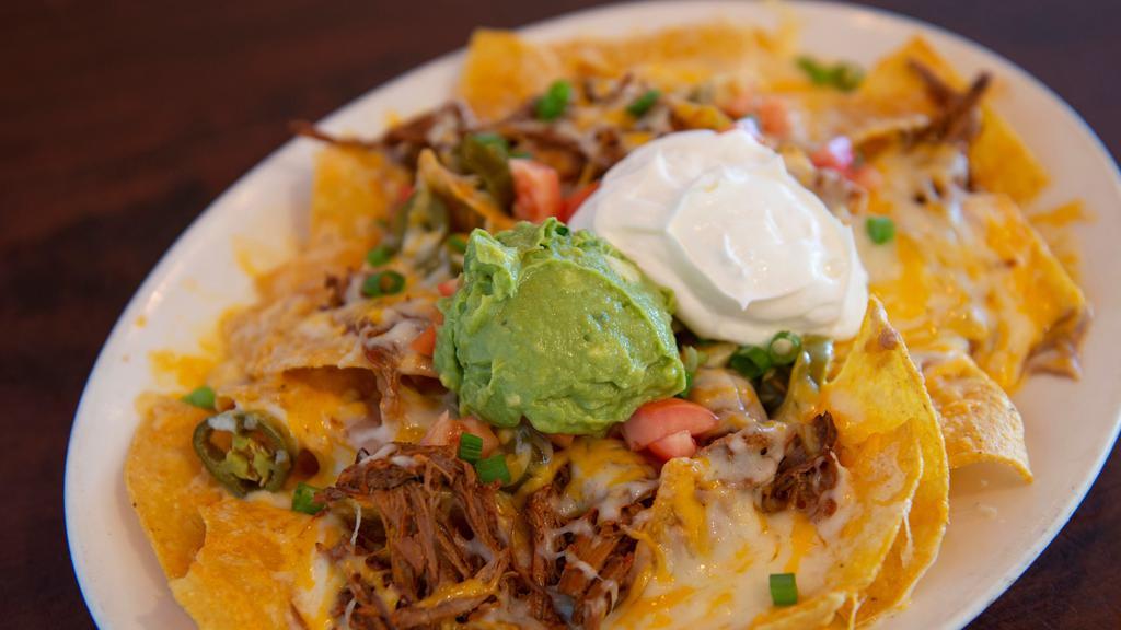 Tapatio Nachos · Corn tortilla chips topped with beans, choice of chicken, picadillo or beef, cheese, sour cream, guacamole, onions, and tomato.