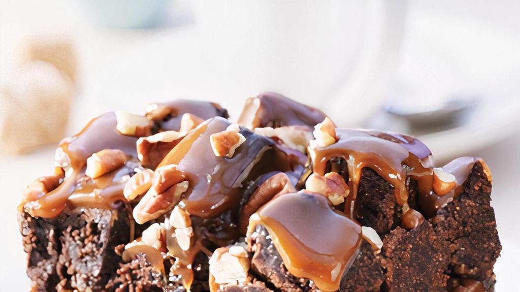 Rockslide Brownie · A light textured Brownie topped with butter-luscious caramel, piled high with Brownie cubes, toasted pecans and drizzle with caramel ganache