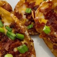 Slate Skins · Potato skins topped with cheese bacon and green onion, served with sour cream.