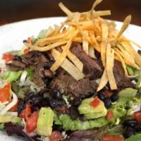 Parrilla Taco Salad · The classic with grilled carne asada steak, black beans, corn tomatoes, tortilla strips, gua...