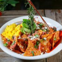 Chilaquiles · Shredded pork, jalapenos, bacon and tortilla chips tossed in our spicy chipotle sauce, toppe...