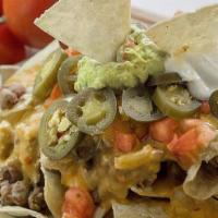 Nacho Supreme · Tostada chips, slow-cooked beans, queso sauce, jalapenos, guacamole, sour cream, and tomato....