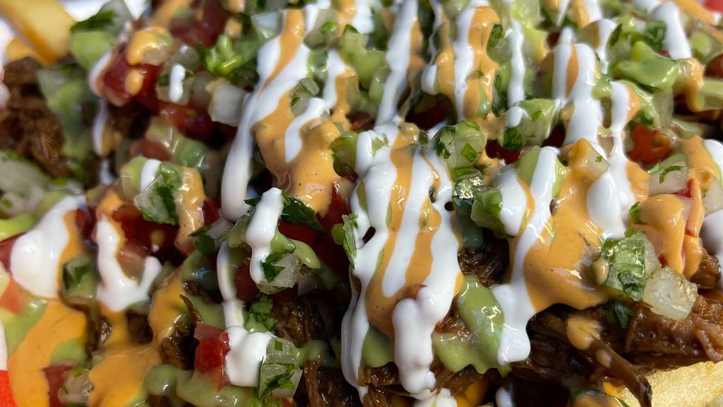 Birria Fries · Steak fries deep fried to perfection and topped with Birria meat, nacho cheese, tomato, raw onion, guacamole sauce, chipotle sauce, and sour cream.