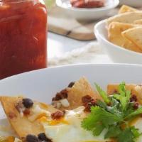 Huevos Rancheros · Crispy flour tortillas, black beans, green chilies, onions and two over-medium eggs with Che...