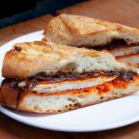 Rotisserie Pork Loin Sandwich · Griddled manchego, caramelized onion, romesco sauce, baguette.