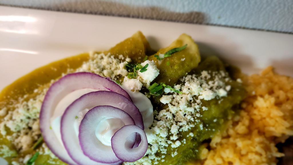 Enchiladas Suizas (Chile Verde) · Three (white meat) chicken enchiladas topped with chile verde sauce and garnished with sour cream and queso fresco. Served with rice and beans.