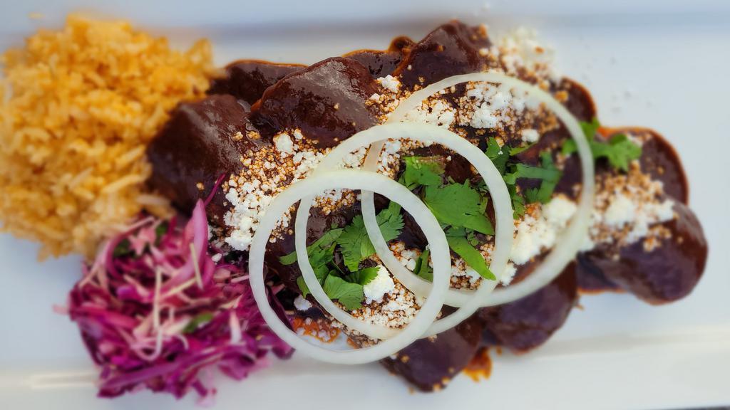 Mole Enchiladas · Three (white meat) chicken enchiladas made with traditional Oaxacan mole sauce, rice, and salad. Topped with queso fresco, cilantro, and onions.