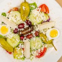 Greek Salad · Crisp lettuce, feta, pepperoncini, tomatoes, cucumbers, rice domades, boiled eggs, and olives.