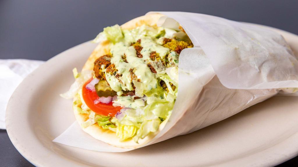 Falafel Pita · Vegan. Chickpea & fava beans ground with vegetables and spices served in a pita bread with lettuce, onions, pickles & tomatoes topped with tahini (sesame seed sauce).