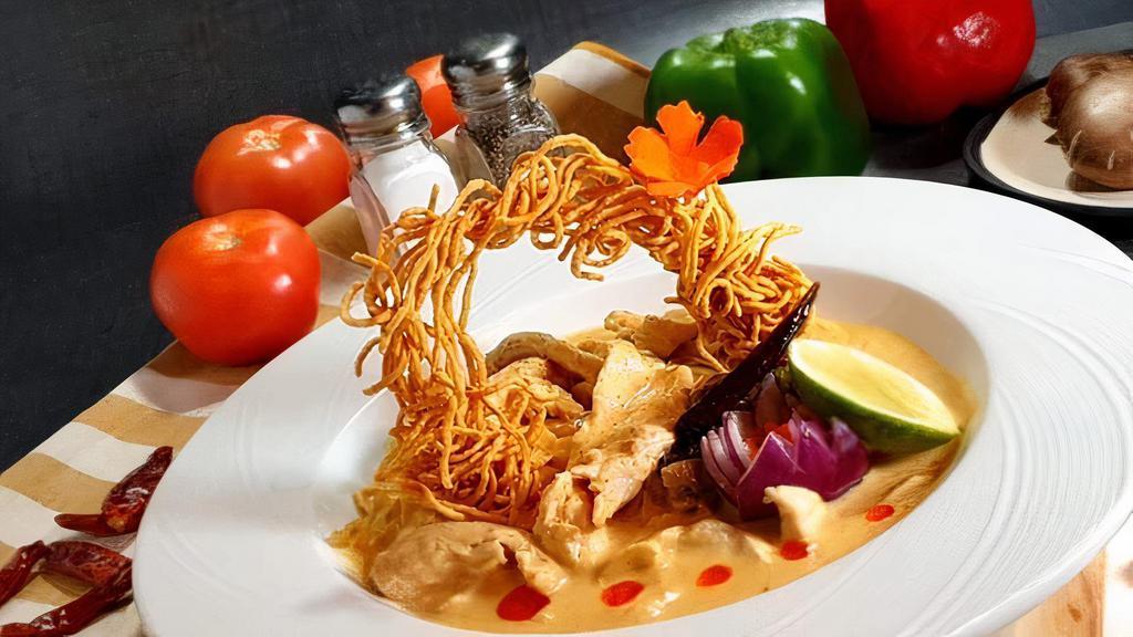 Khao Soi · Traditional northern Thai curry noodle soup served with chicken breast, fried onions, lime, dried chili and pickle cabbage topped with crispy noodle, lime and fresh shallots.