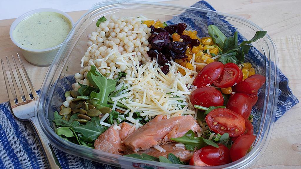Smoked Salmon Salad · Couscous, arugula, house-smoked salmon, tomatoes, shallots, basil, olive oil, roasted corn, cranberries, Parmesan, and pepitas with our creamy pesto dressing. Please no substitutions or modifications.