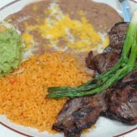 Carne Asada · Tender skirt steak with refried beans with cheese, guacamole salad and three flour tortillas.