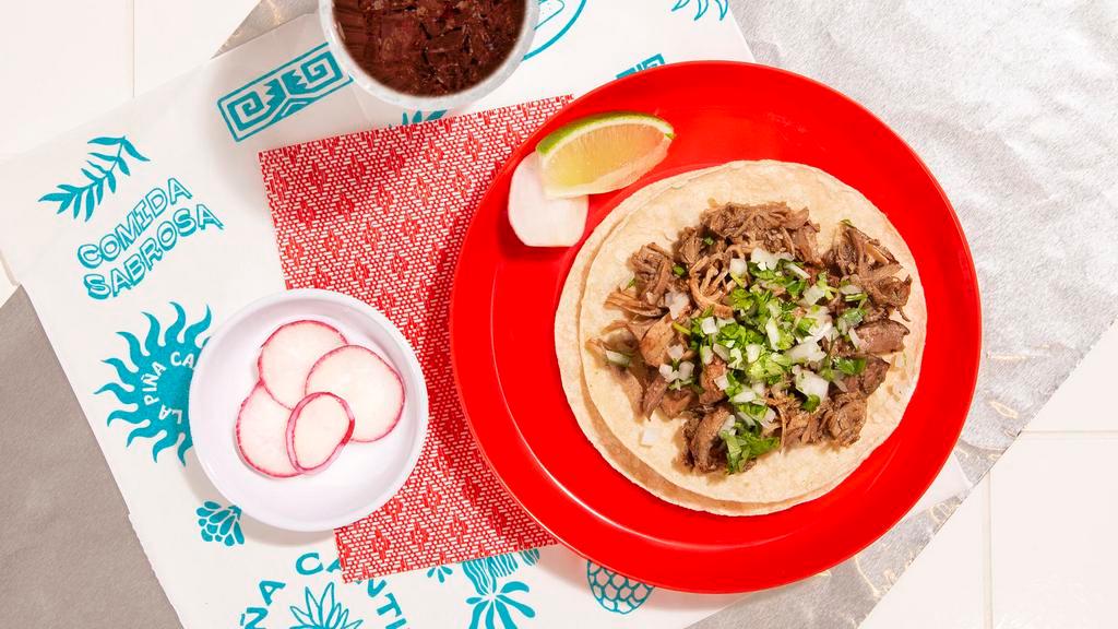 Carnitas Taco · Braised pork topped with cilantro and chopped onion on a soft corn tortilla.