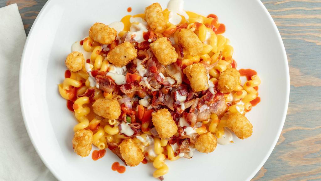 The Works · Cheddar Mac, Bacon, Sauteed Red Bell Peppers and Onions, topped with Tater Tots and Drizzled with Sriracha, served with Ranch.
