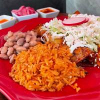 Enchilada Plate · Three corn tortillas in deep homemade sauce with shredded chicken, rice, beans, lettuce, fre...