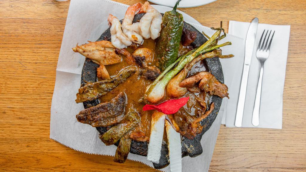 Molcajete Trio · Grilled shrimp, chicken and beef served in molcajete bowl with chorizo sauce. Topped with grilled onion, jalapeño and cheese. Your choice of charro or refried beans.