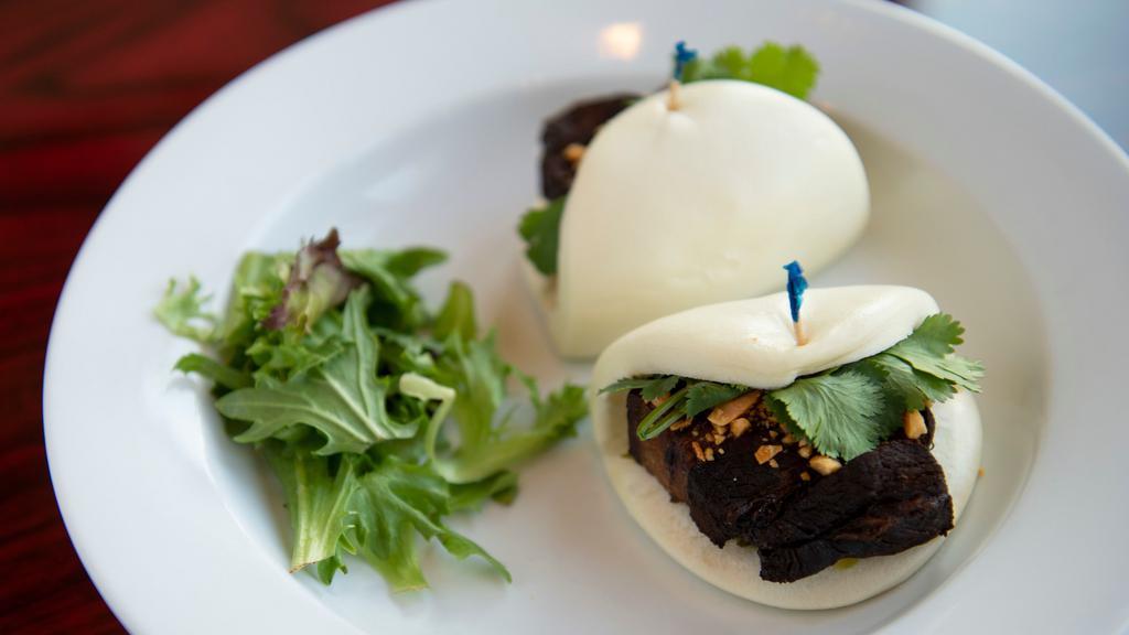 Pork Belly Buns · Braised pork belly served in steamed buns with pickled greens, crushed peanuts, and cilantro.