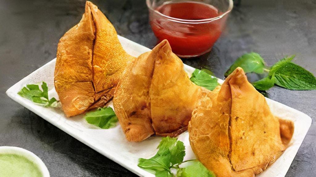 Samosa · A delectable duo of handmade crisp cones filled with potatoes, peas, cumin, spiced, and seasoned. Served with house special tamarind and mint chutney.