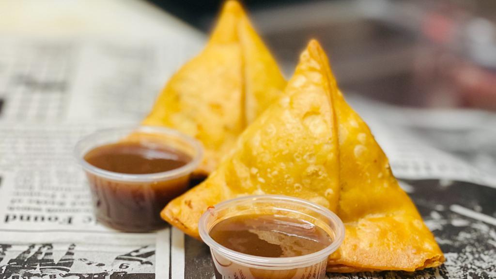 Two Vegetable Samosas · Two Jumbo potato and peas filled samosas. Flaky outer shell. Served with a side of sweet-sour tamarind chutney.