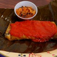 Tamales · With banana leaves,and chicken and tomato sauce on the side.