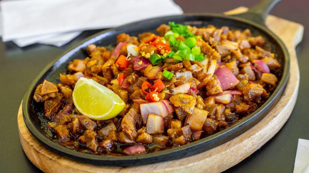 Sisig · Minced pork marinated in calamansi juice (Philippine lemon), onions tossed in a tangy sauce topped with chili and green onions.