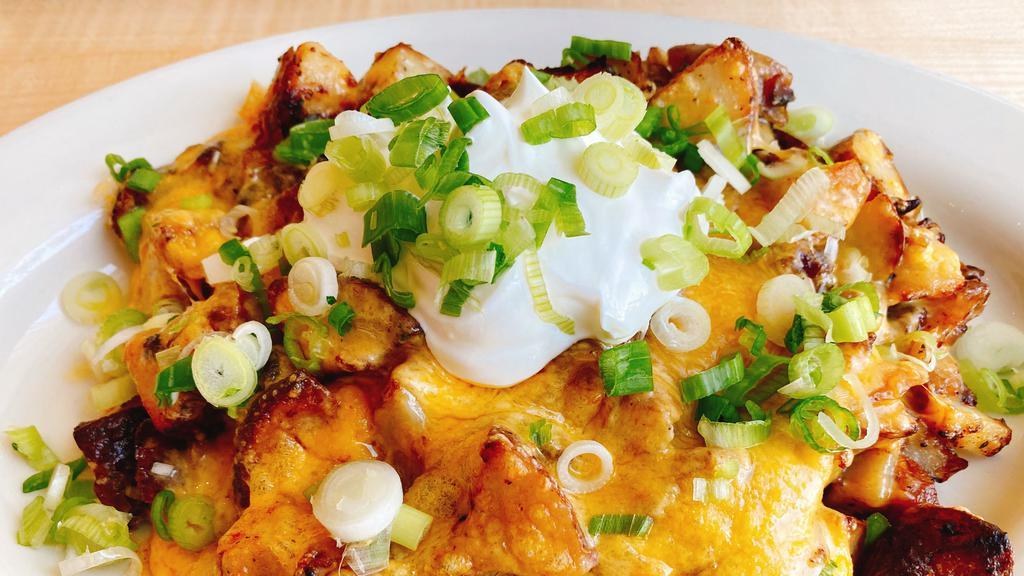 Irish Nachos · Roasted potatoes, bacon, caramelized onions and a touch of cream, topped with melted cheddar cheese, sour cream,  and green onions.