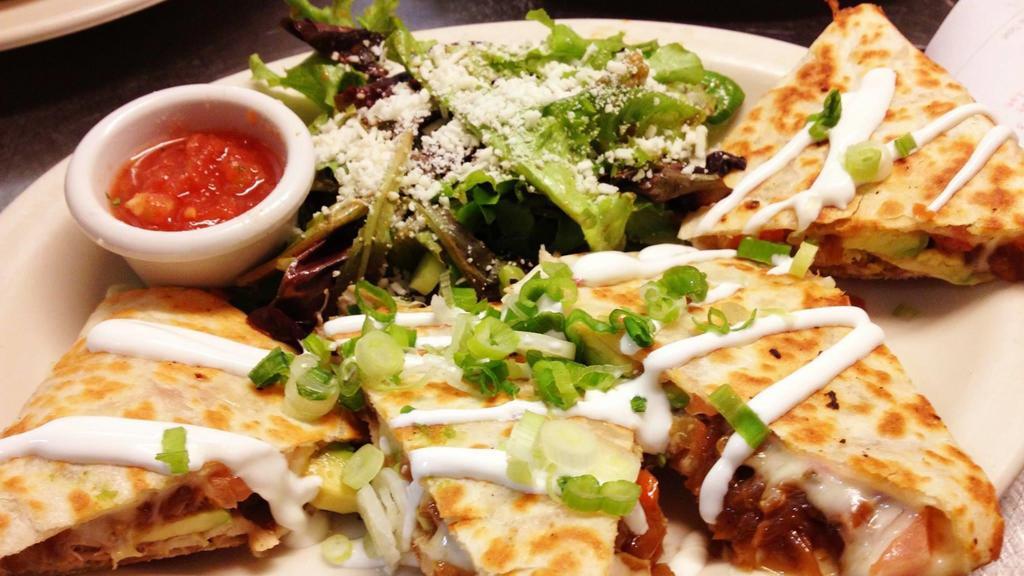 Pulled Pork Quesadilla · Carlton Farms slow-cooked pork, caramelized onions, jack cheese, flour tortilla, chipotle sour cream, green onions, honey-lime dressed greens, and cotija cheese.